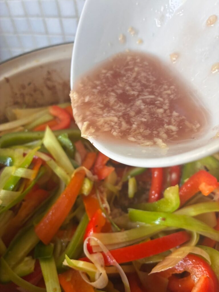 zoet-zuur varkensvlees met ananas knoflook dressing over de groenten in de pan