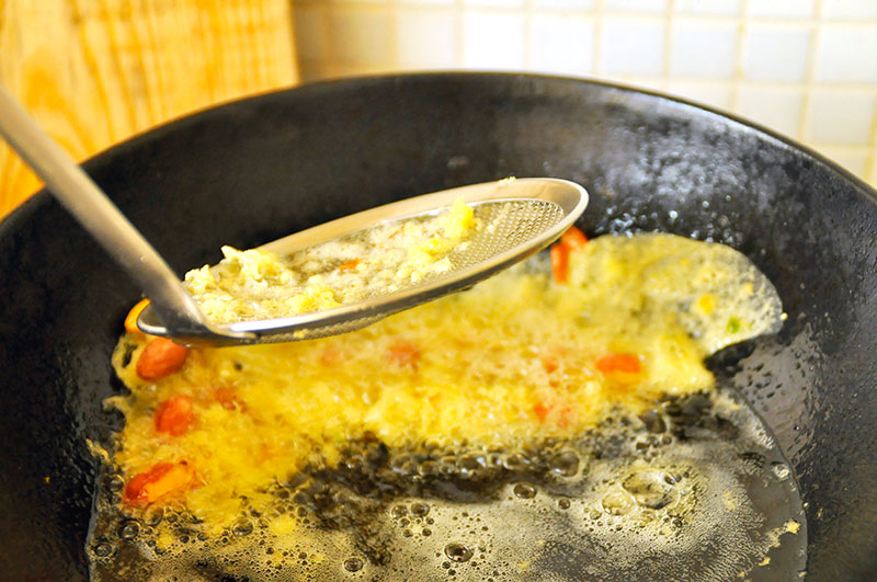 Rempeyek frituren en overgieten met olie om los te komen van de kant